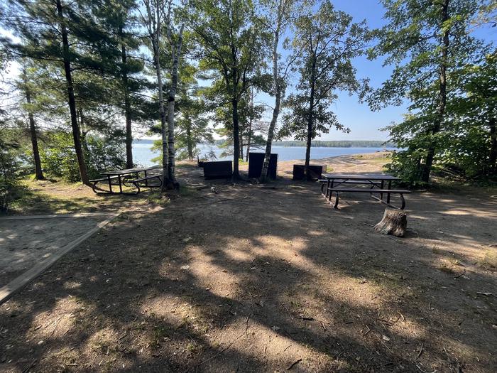 K1 View looking out from campsite core of a tent pad picnic tables bear lockers and fire ring with water in the background.