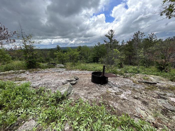 H2 Blueberry Ridge primitive campsite view looking out across ridge with the fire ring on rocky outcropping and trees in the background.