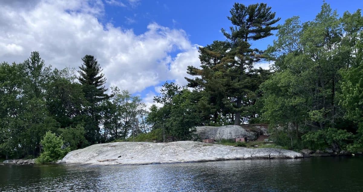 K9 Grassy Islands South view of campsite core from water on rocky point with a few trees in the background.