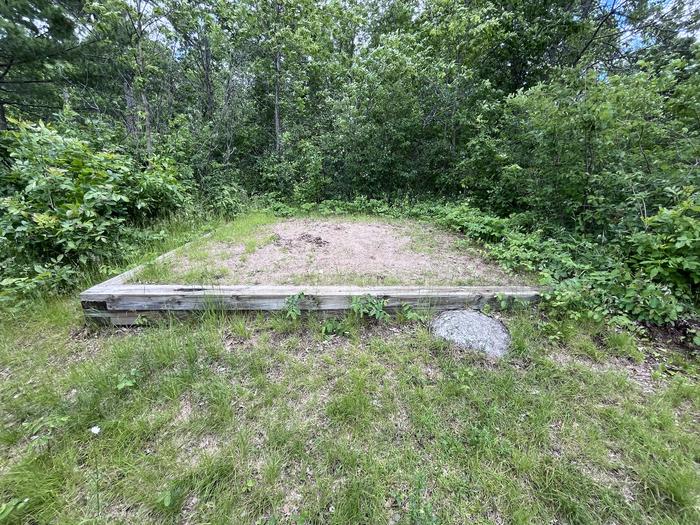 K11 Happy Landing tent pad #2 at campsite with greenery in the background.