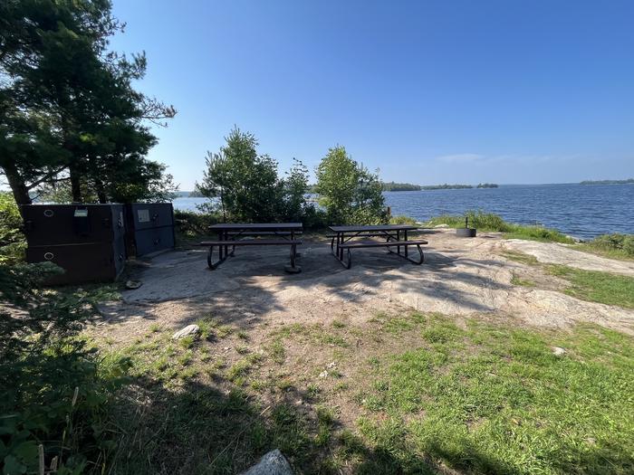 K55 View looking out from campsite core of the bear lockers picnic tables and fire ring with water in the background.