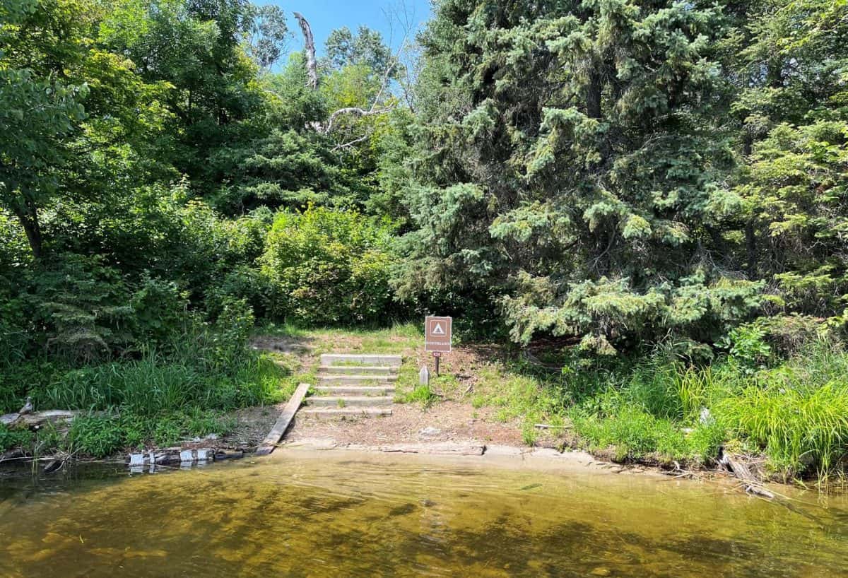 K24 View of sand landing at campsite from water with stairs leading from shore and the campsite sign.