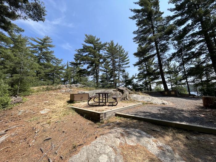 K25 View looking into campsite with a couple of bear lockers and picnic table in the main gravel area of the campsite.