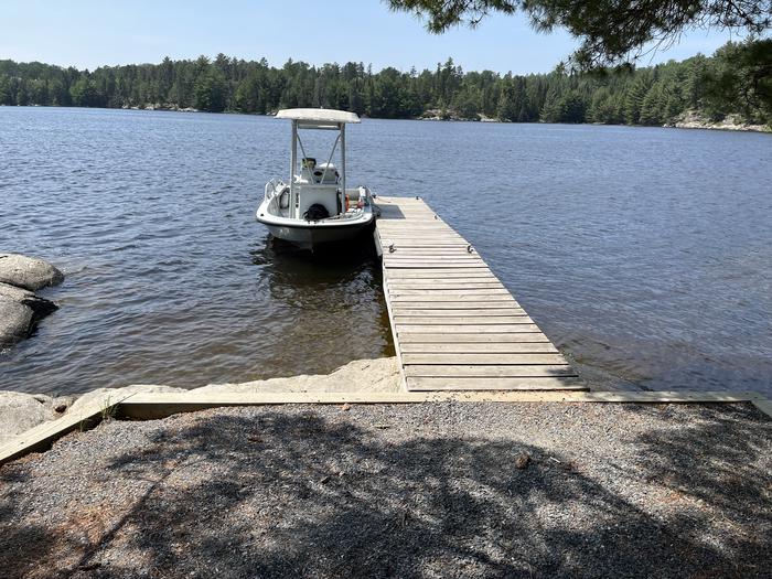 K25 View looking out from shore of the wood dock landing with a white boat tied to the dock.